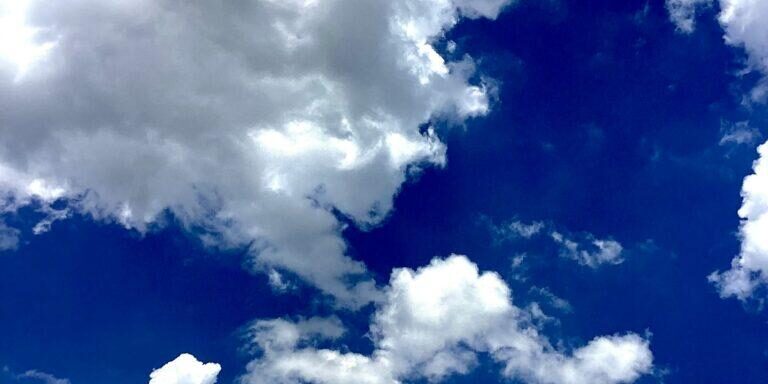 Bright white clouds over a vivid deep blue sky